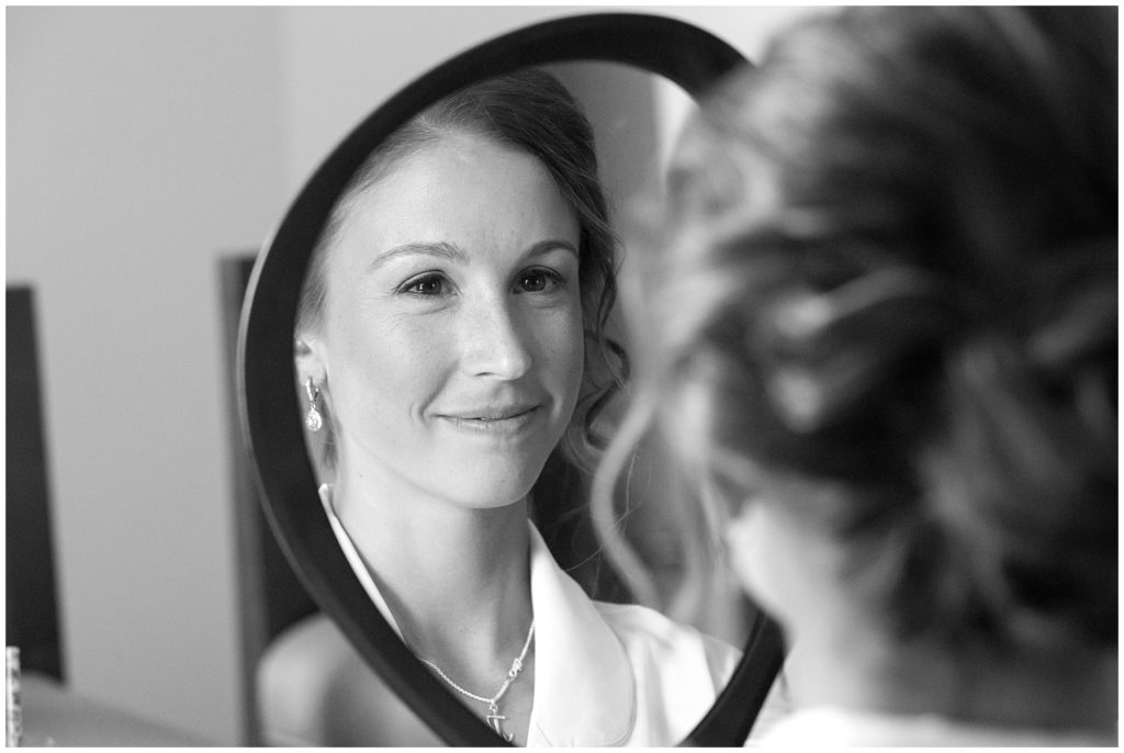 The bride looks at her makeup in the mirror. 