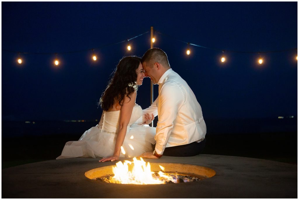 Bride and Groom sitting by a fire pit out side at the Warwick Country Club in Warwick Rhode Island. 